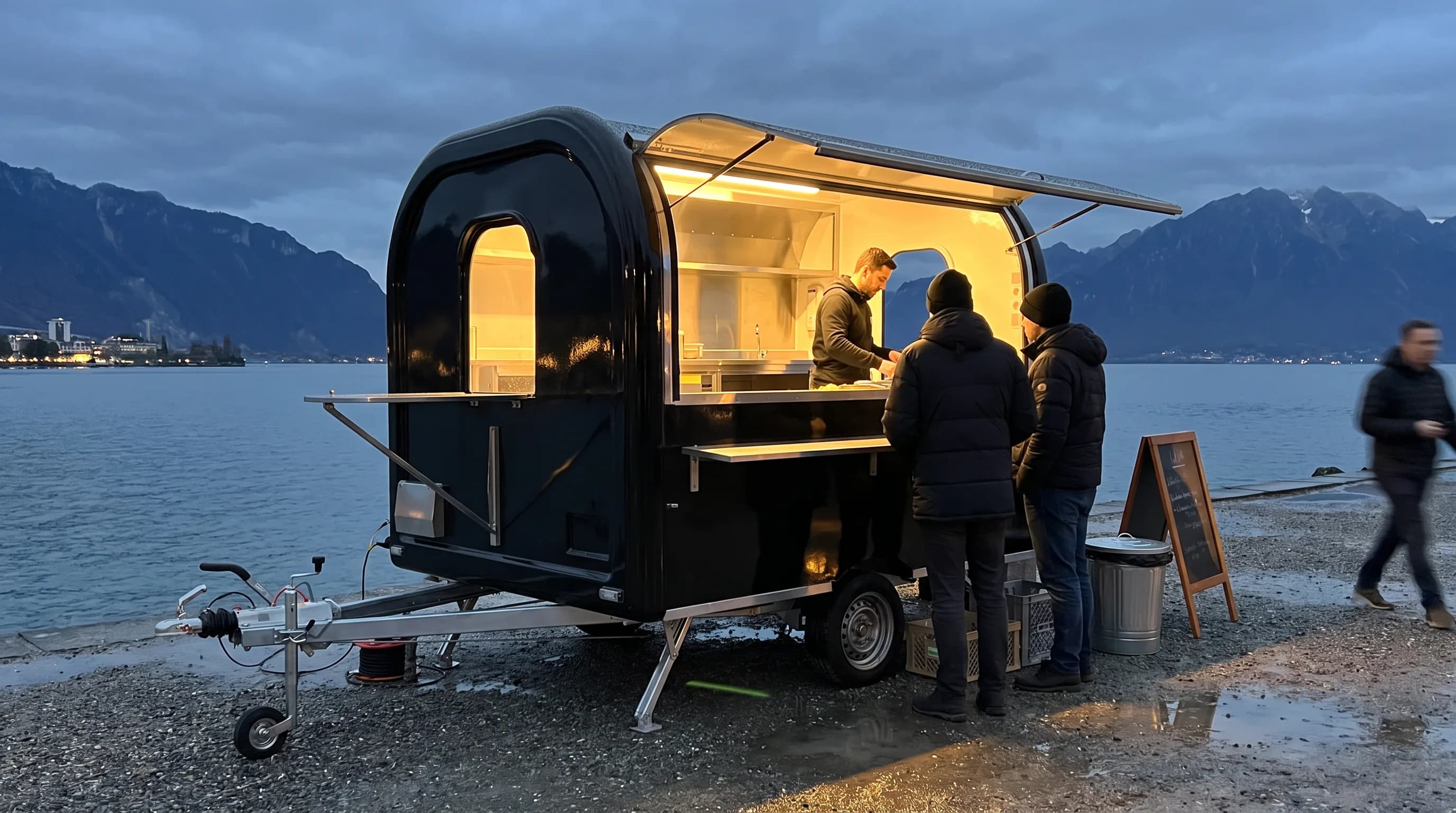 Remorque food truck noire en service au bord du lac Léman à la tombée de la nuit